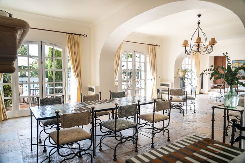 Provencal venue interior with vaulted white arched ceilings, wrought-iron tables, mosaic tiles, and arched French doors