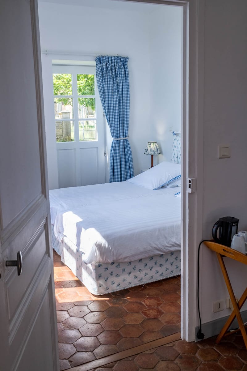 French country guest bedroom with blue gingham curtains terracotta tiles and white linens