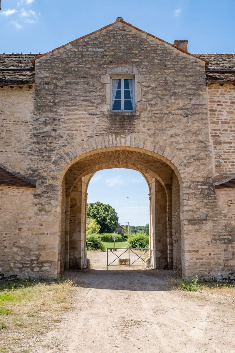 Stone archway entrance gateway of rural French estate with clay tile roof and countryside view