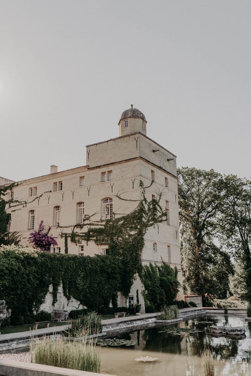 French chateau exterior with domed turret climbing ivy and formal reflecting pool with lily pads