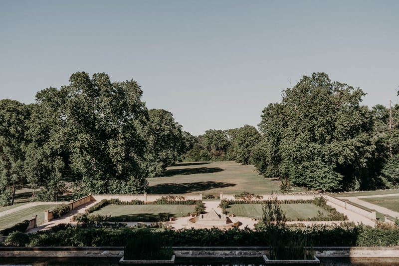 Elevated view of formal French parterre garden with clipped hedgerows, gravel paths and central fountain