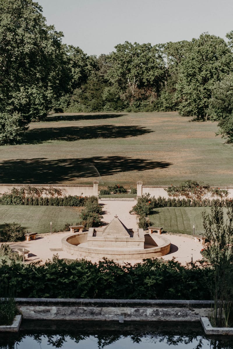 Formal French chateau garden with reflecting pool, stone staircase, and symmetrical parterre leading to open lawn