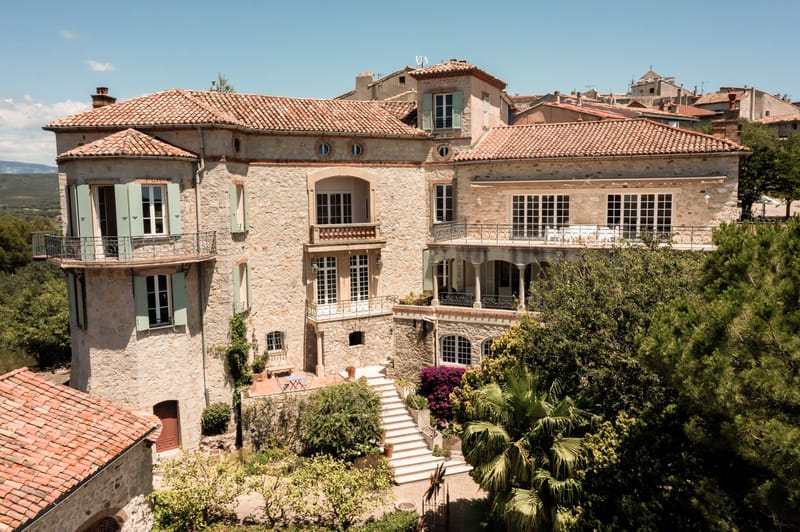 Aerial Provencal stone manor with terraced garden, columned terrace, and bougainvillea in hilltop village