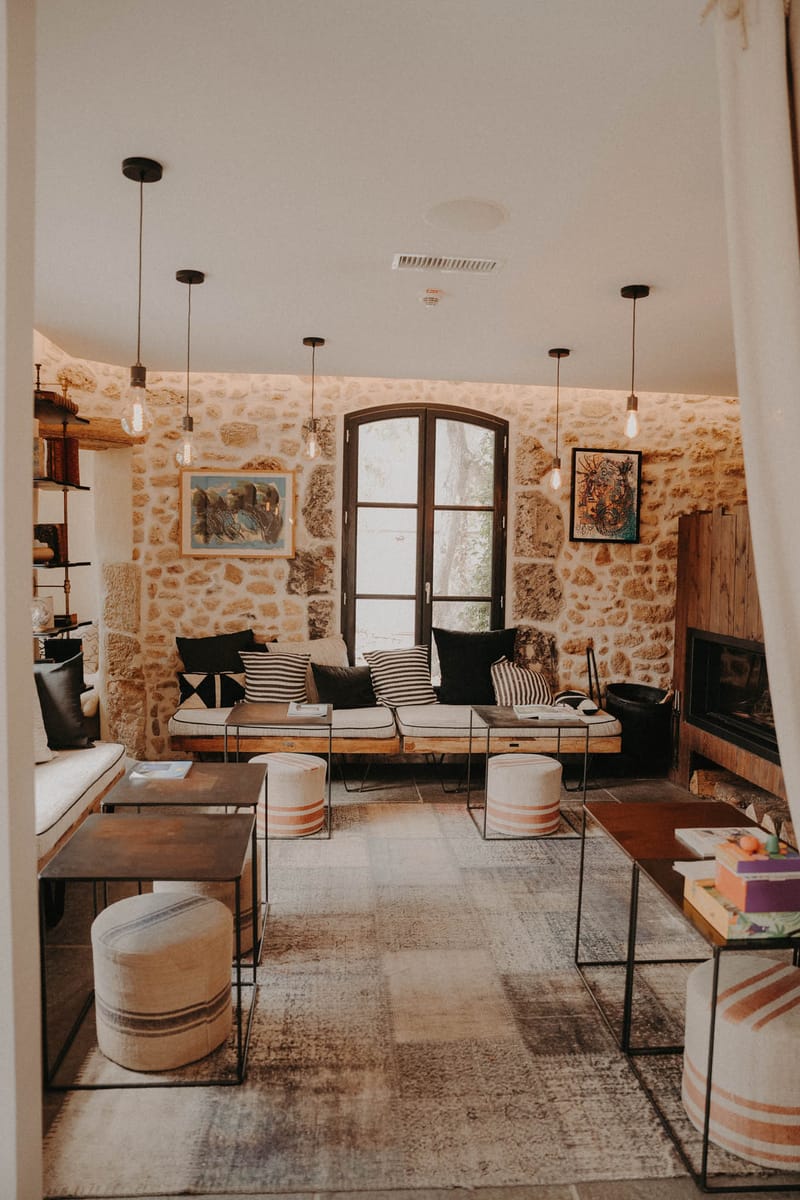 Rustic-modern lounge with golden limestone walls Edison pendants linen poufs and wire side tables