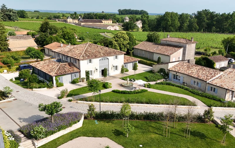 Aerial drone view of whitewashed wine estate with courtyard fountain vineyards and outbuildings