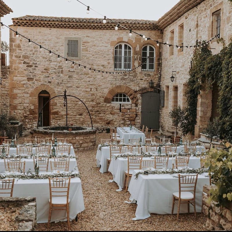 Reception tables with eucalyptus garlands and gold chiavari chairs in stone courtyard with string lights overhead