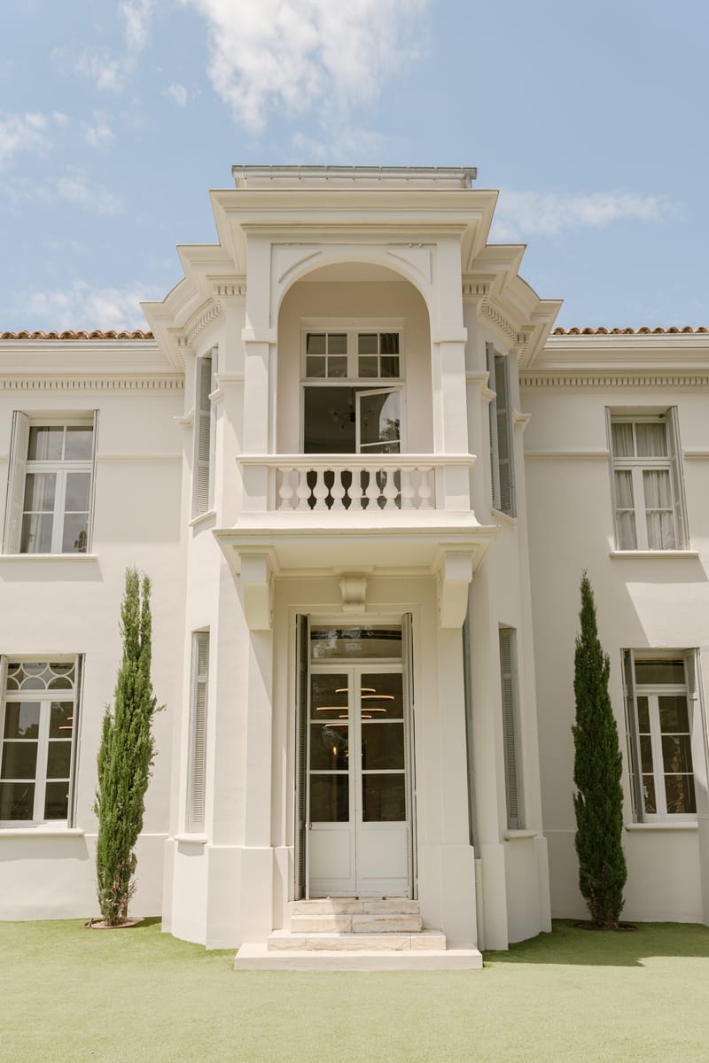 White rendered villa with balustraded balcony arched portico terracotta roof cypress trees and symmetrical facade