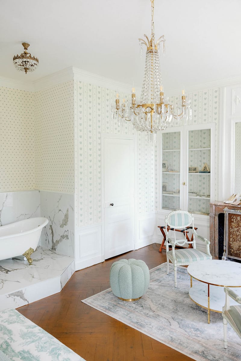 Chateau bridal suite with clawfoot bathtub, floral wallpaper, crystal chandelier, and mint green furnishings