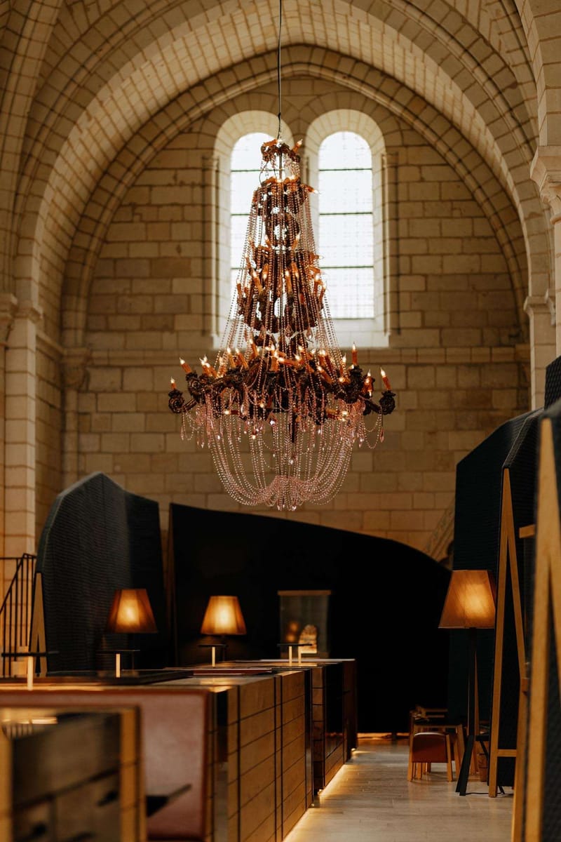 Converted Romanesque chapel with crystal chandelier, barrel vault ceiling, and modern charcoal partitions