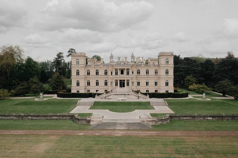 Grand neoclassical chateau with symmetrical facade, towers, and formal stone staircase