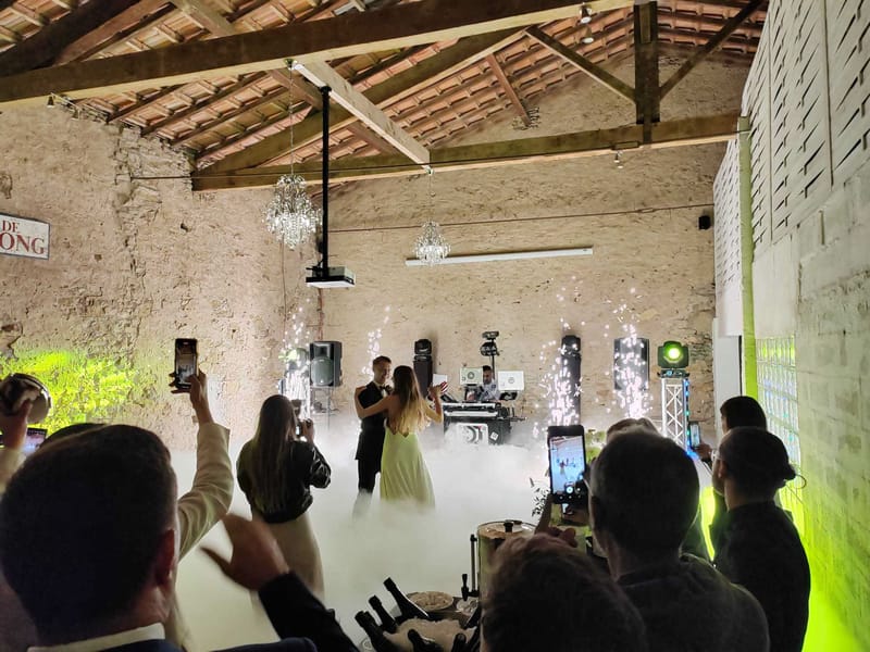 Couple first dance in rustic stone barn with dry ice fog and cold spark fountains, DJ booth behind