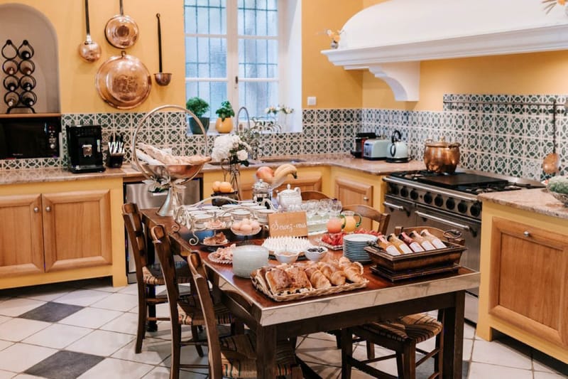 French country kitchen with copper pans, checkered floor, and breakfast buffet spread