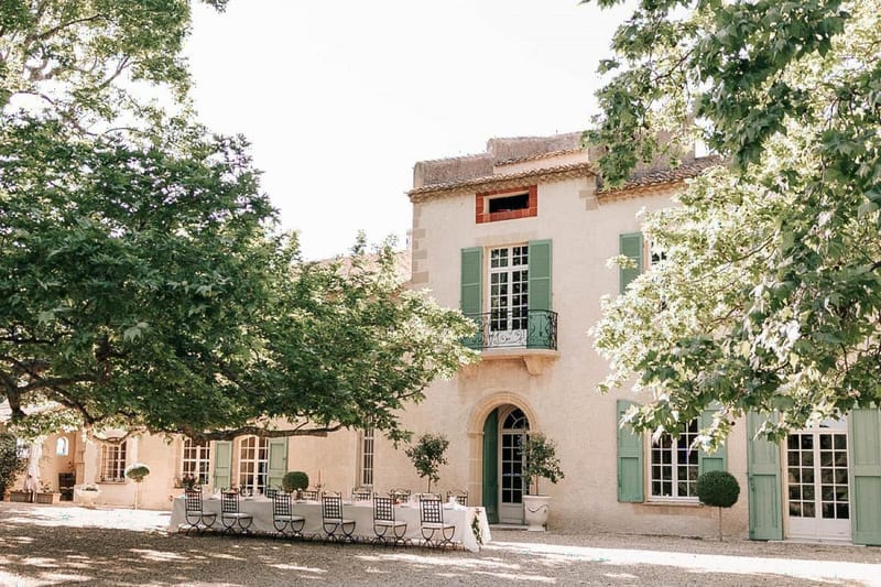 Provencal mas with sage shutters, arched doorways, and long white reception table with boxwood topiaries