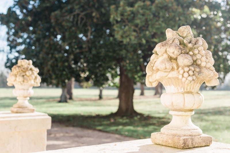 Ornate carved stone urns with fruit motifs on balustrade at French chateau formal garden