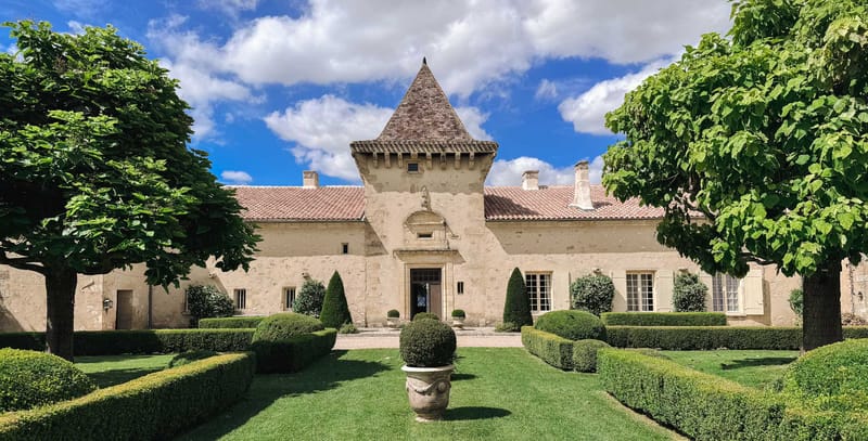 French chateau exterior with pointed stone tower, limestone walls, and formal parterre garden with clipped boxwood hedges