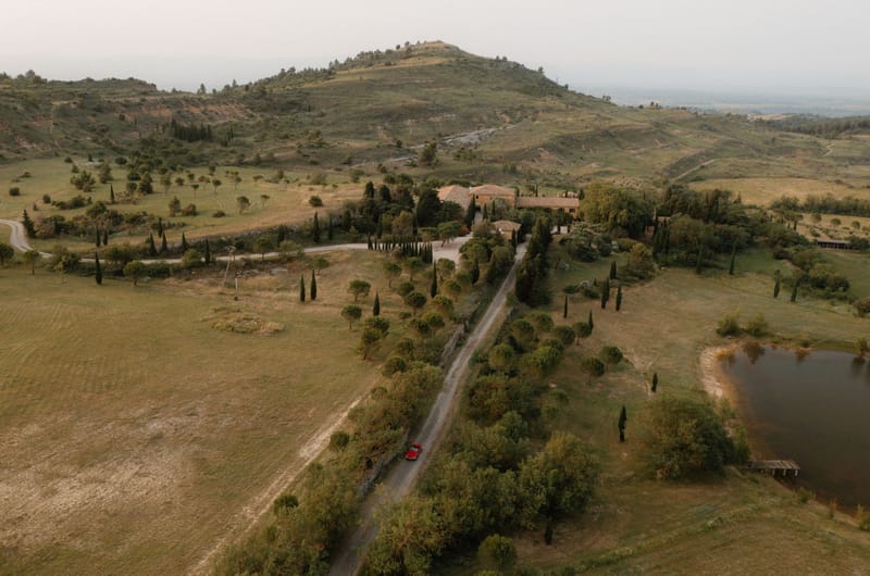 Aerial view of Provencal estate with cypress-lined driveway and red vintage car approaching