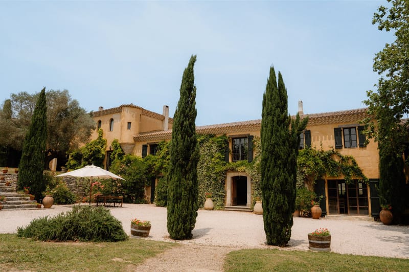 Ochre Provencal mas with ivy-covered facade terracotta urns cypress-lined courtyard and wine barrel planters