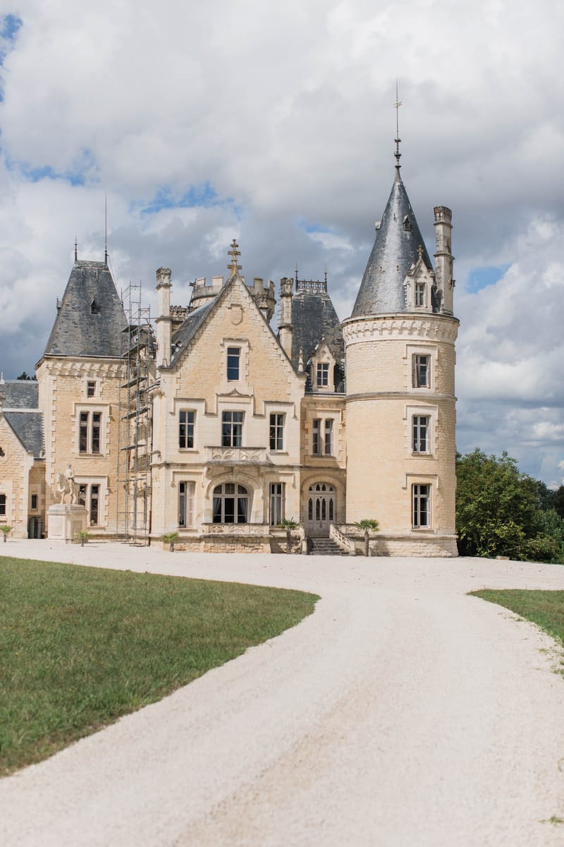 French chateau with cream limestone, slate-roofed conical towers, and Gothic-Renaissance detailing