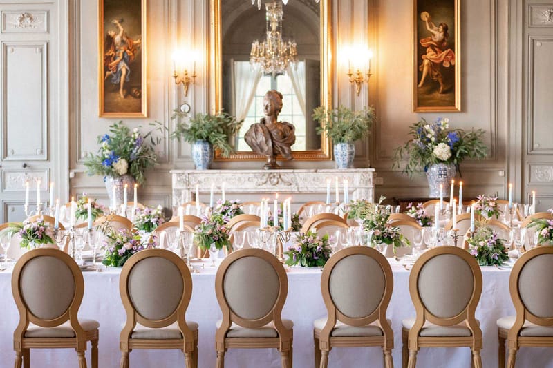 Banquet table with mauve florals and silver candelabras in grey-panelled ballroom with crystal chandelier