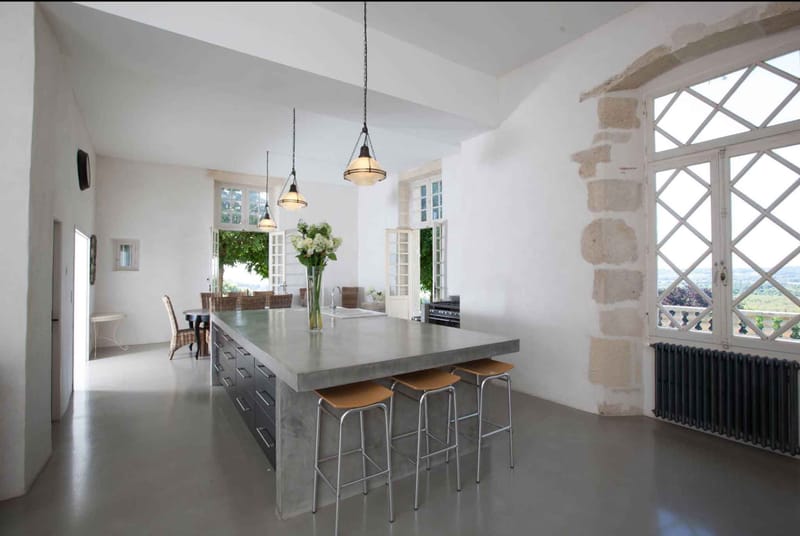 Open-plan chateau kitchen with concrete island pendant lights diamond-pane windows and countryside view