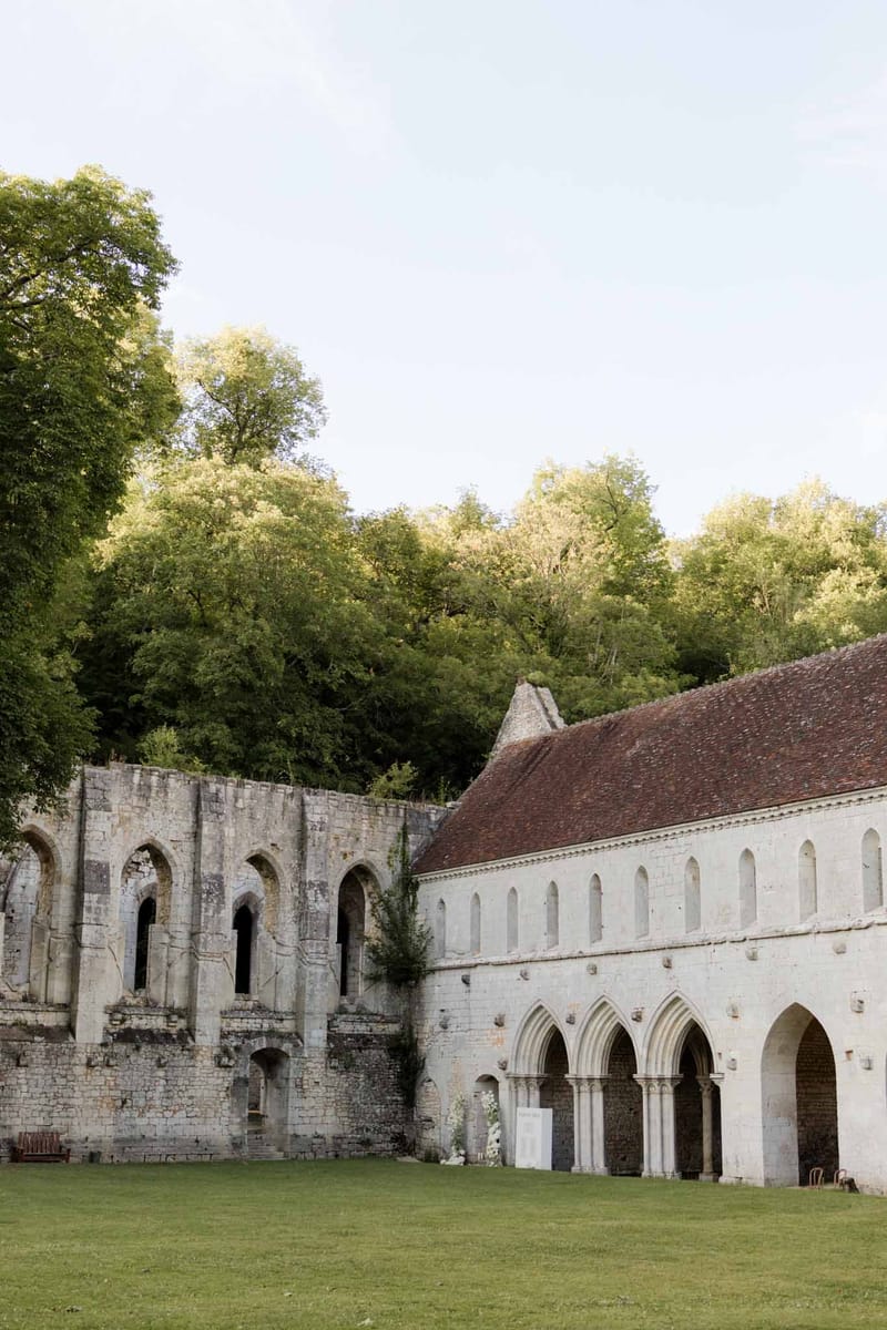 Ruined stone abbey with Romanesque arches and Gothic windows set in wooded grounds