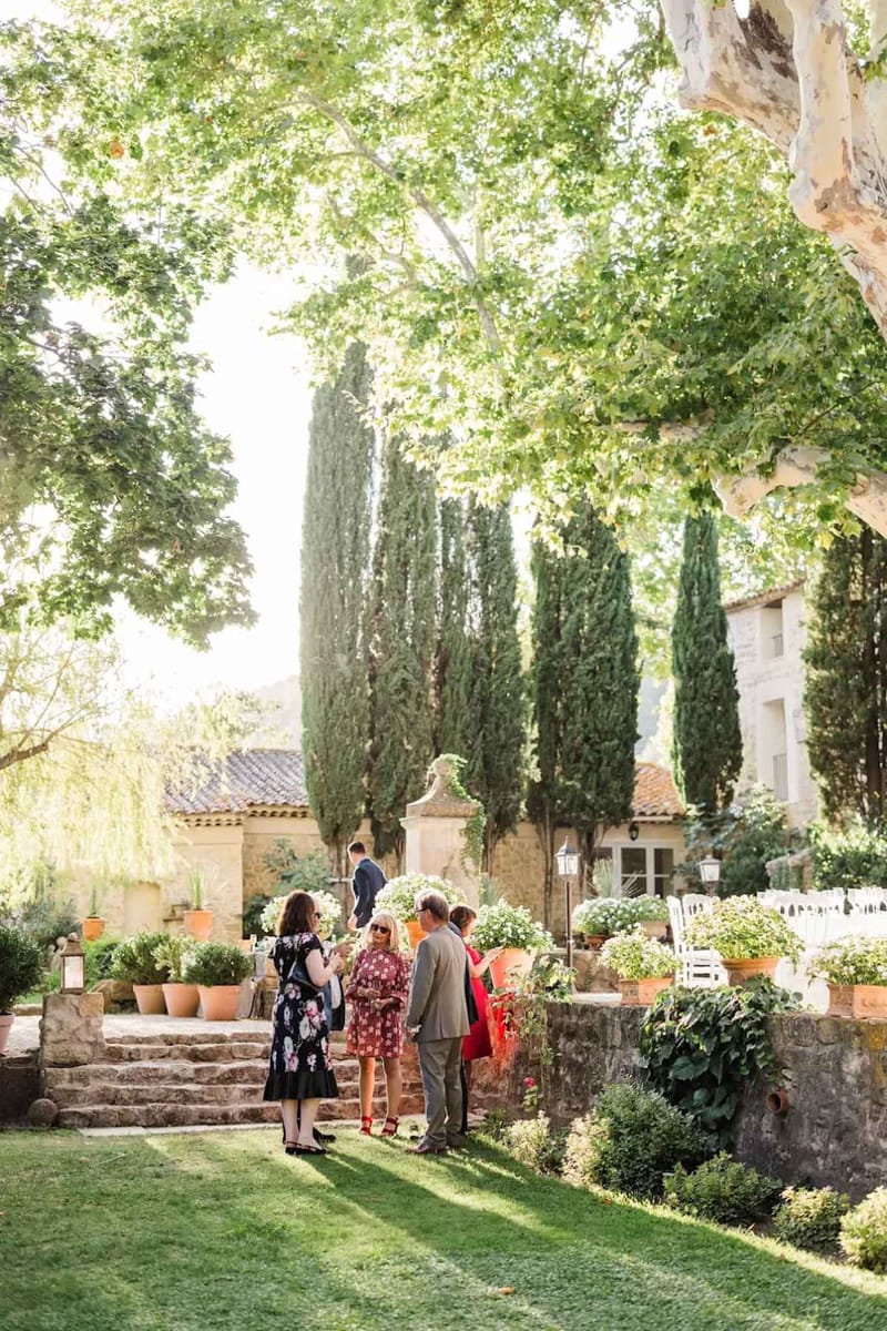 Guests mingling on stone steps during cocktail hour at a Provencal stone property with cypress trees