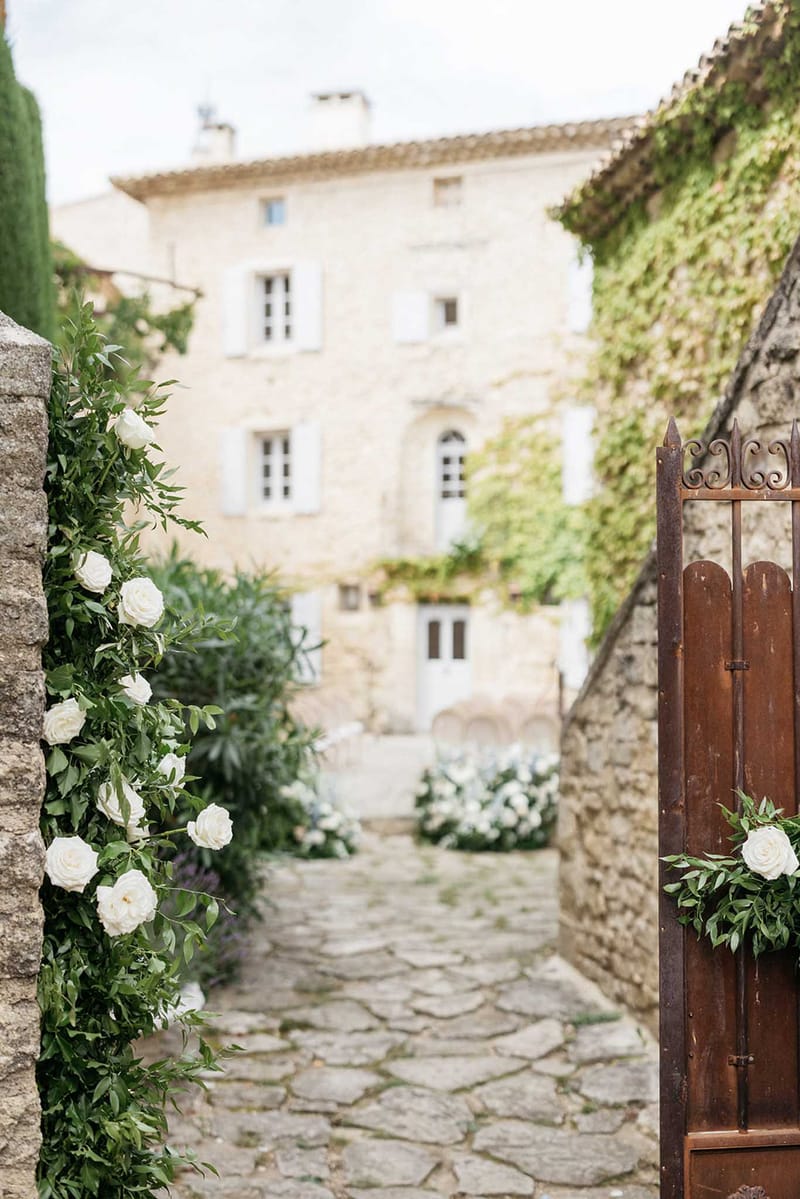 Stone courtyard passageway with ivory roses and wooden gate at historic European wedding venue