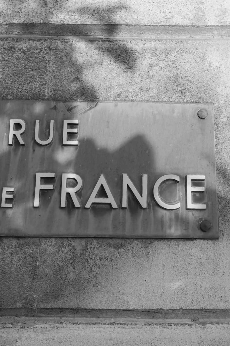 Metal street plaque reading Rue de France mounted on textured stone wall at French wedding venue