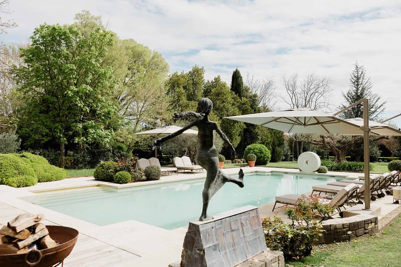 Poolside wedding venue with bronze sculpture, umbrellas and lounge seating at modern outdoor space