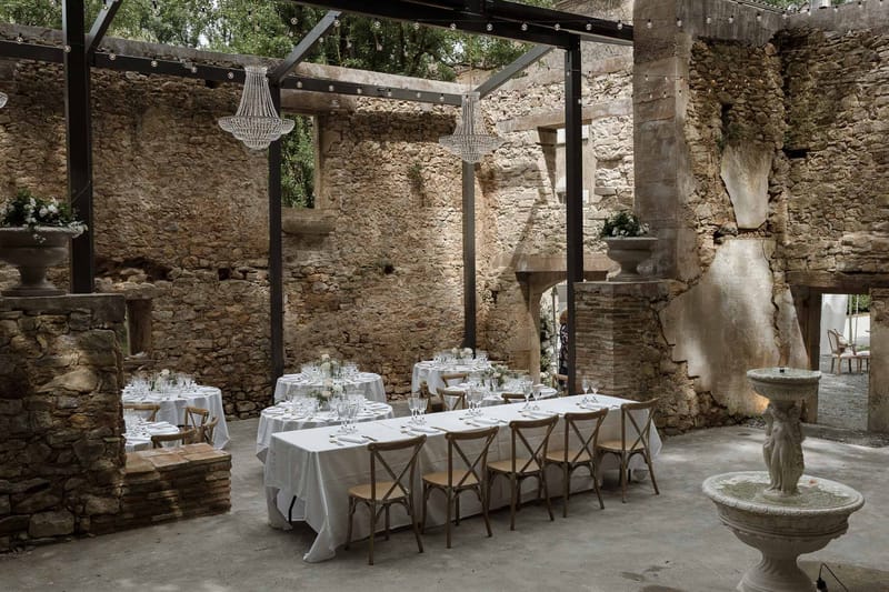 Wedding reception setup in historic stone courtyard with round tables and chandelier lighting