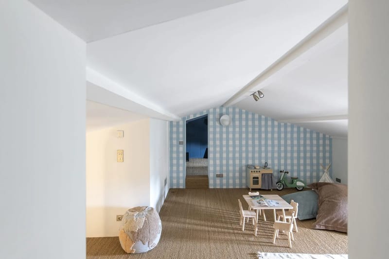 Children's playroom with gingham wallpaper, wooden toy kitchen, tipi tent, and small furniture