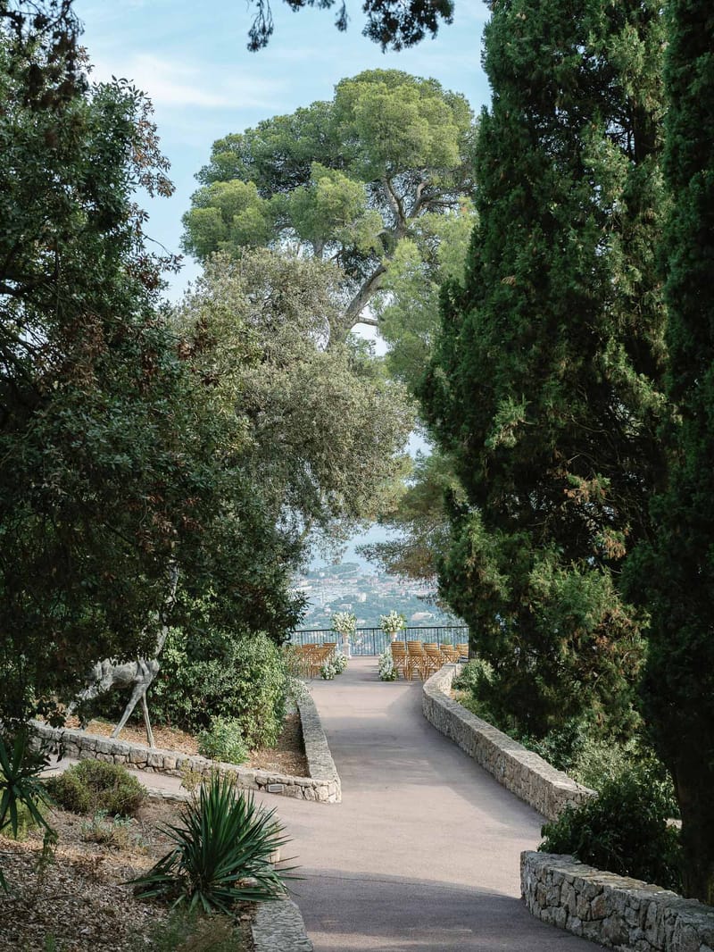 Mediterranean garden pathway with cypress trees and ceremony setup at hillside wedding venue