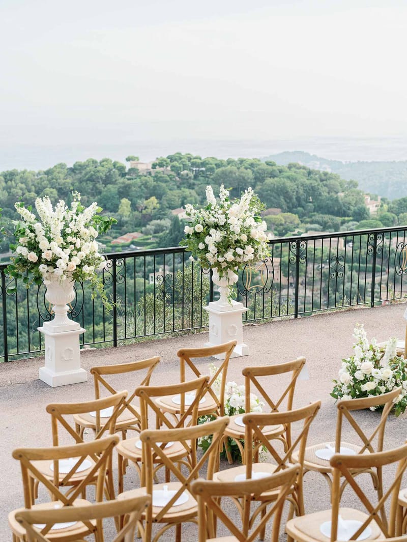 Outdoor ceremony setup on terrace overlooking Tuscan landscape with white floral arrangements