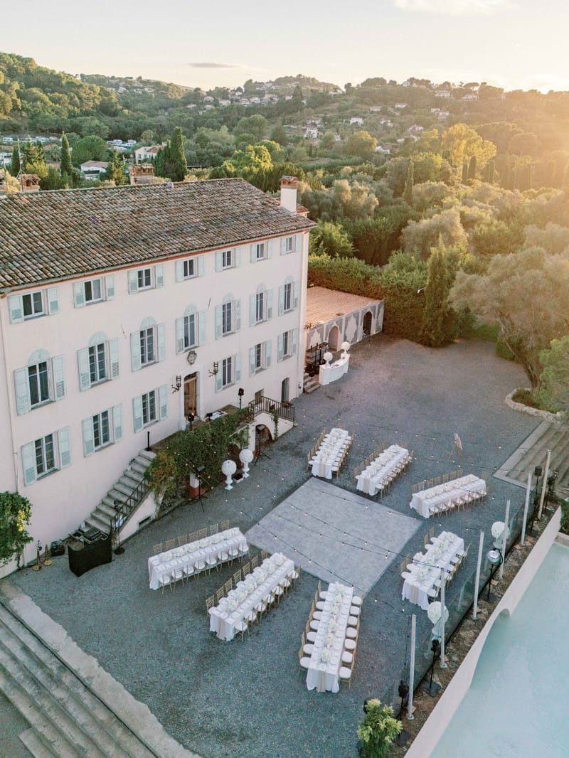 Aerial view of outdoor wedding reception with long white tables and gold chairs in Provencal bastide courtyard