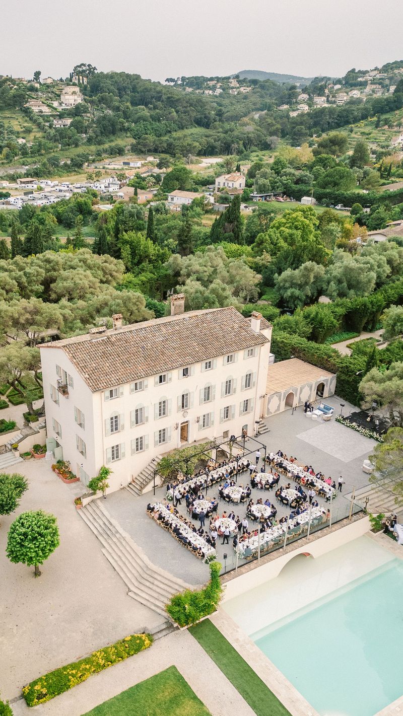 Aerial view of outdoor wedding reception with round tables in courtyard of Provencal bastide villa