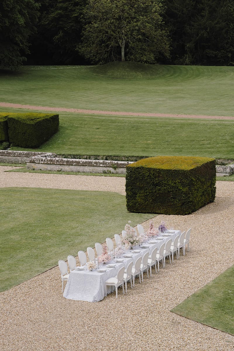 Aerial view of outdoor reception table setup in formal château garden with manicured hedges and topiary