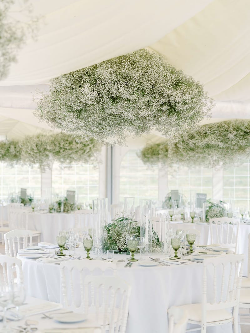 White marquee reception with suspended gypsophila cloud installations and green hobnail glassware