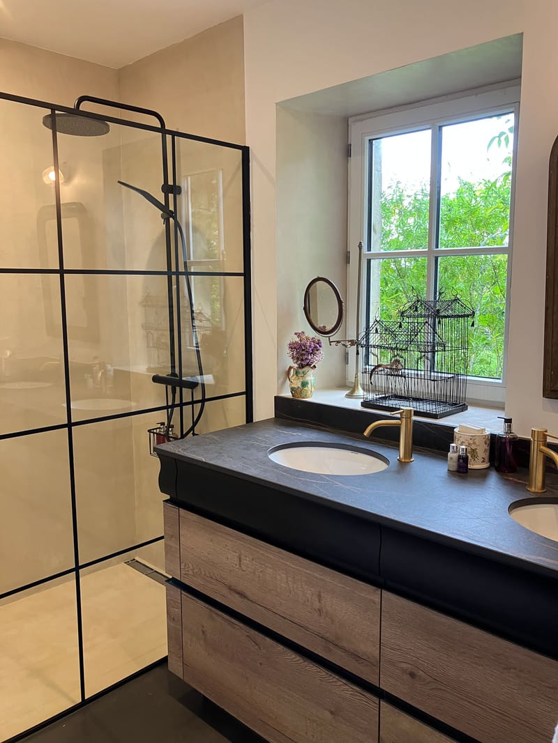 Contemporary bathroom with double vanity, dark stone countertop, brass fixtures, and crittall-style glass shower