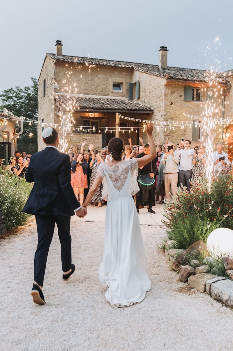 Bride and groom make grand entrance through cold sparkler fountains at outdoor Provencal farmhouse evening reception