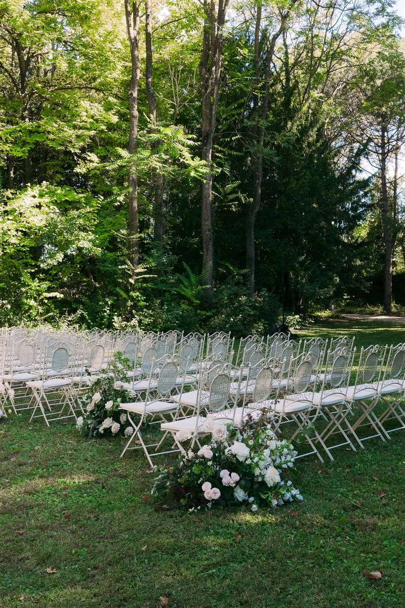Outdoor wedding ceremony setup with chairs arranged under trees in garden venue
