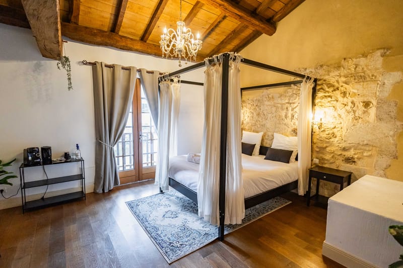 Stone-walled bedroom suite with four-poster bed crystal chandelier and dark wood beams