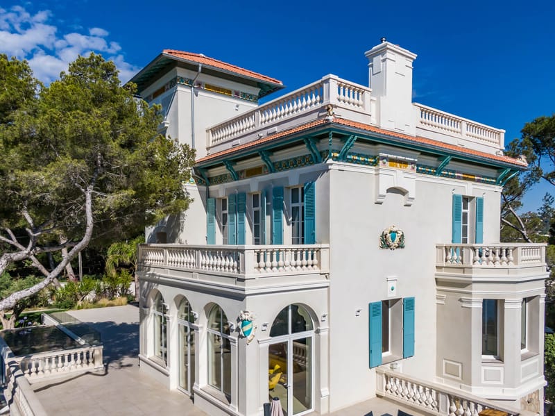 Aerial view of Belle Epoque villa with white facades terracotta roof and teal shutters surrounded by manicured gardens