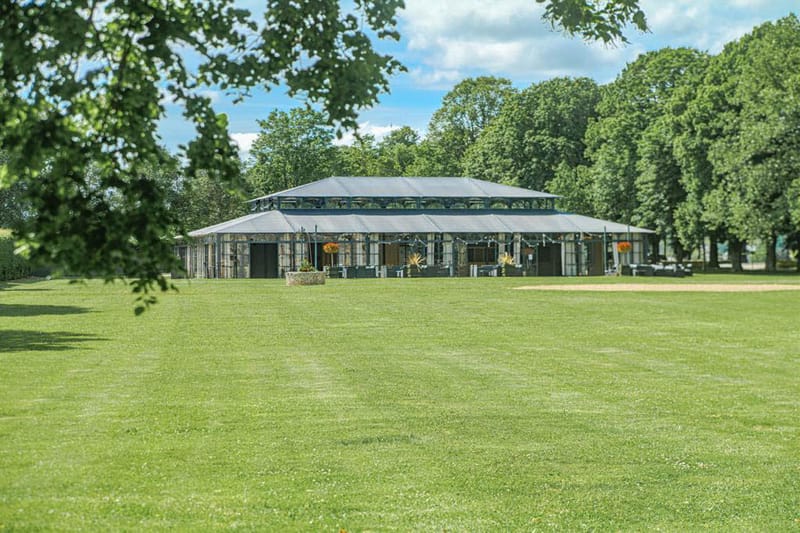 Glass pavilion wedding venue on a parkland estate lawn with fairy lights and floral arrangements inside