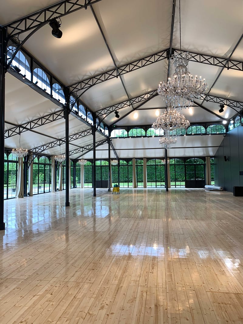 Empty marquee-style reception hall with crystal chandeliers wrought-iron framework and polished parquet floor