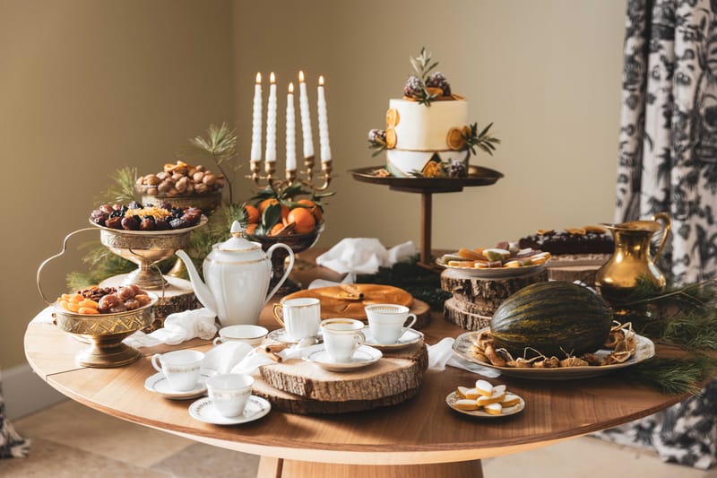 Rustic dessert table with two-tier wedding cake, brass candelabra, dried fruits, and gold serving pieces