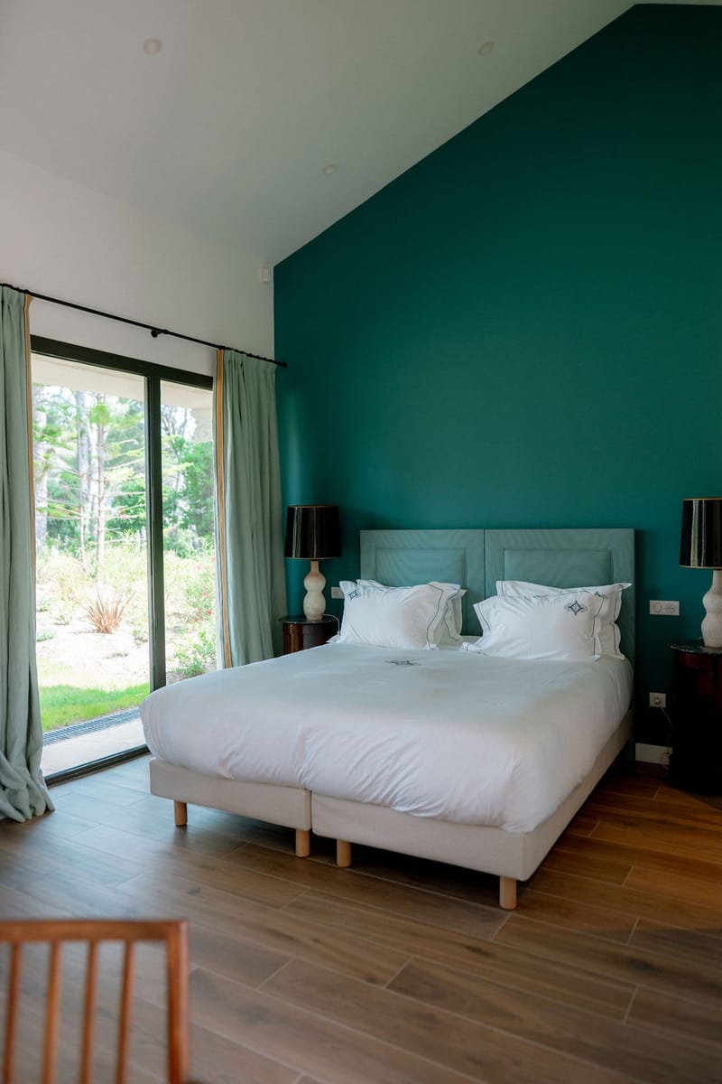 Teal-walled guest bedroom with garden view at Domaine Rocabella, French Riviera