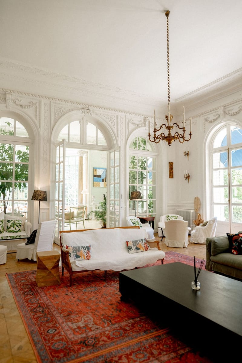 Grand white salon with Persian rug and arched mirrors at Domaine Rocabella, French Riviera