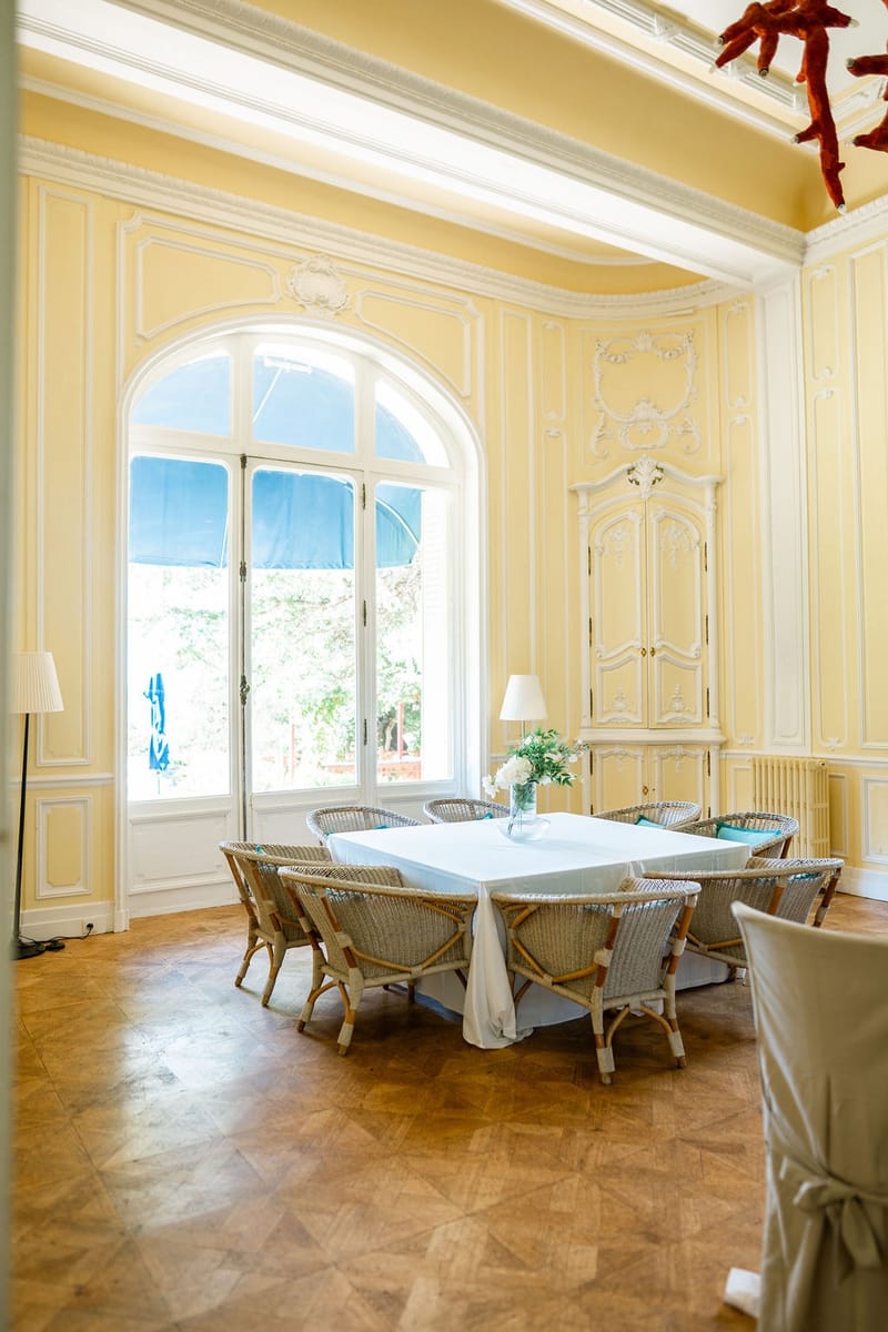 Yellow dining room with rattan chairs and garden views at Domaine Rocabella, French Riviera