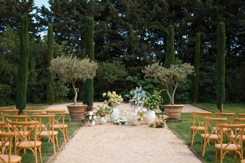 Mediterranean garden ceremony setup with cross-back chairs and hydrangea arrangements at outdoor wedding venue
