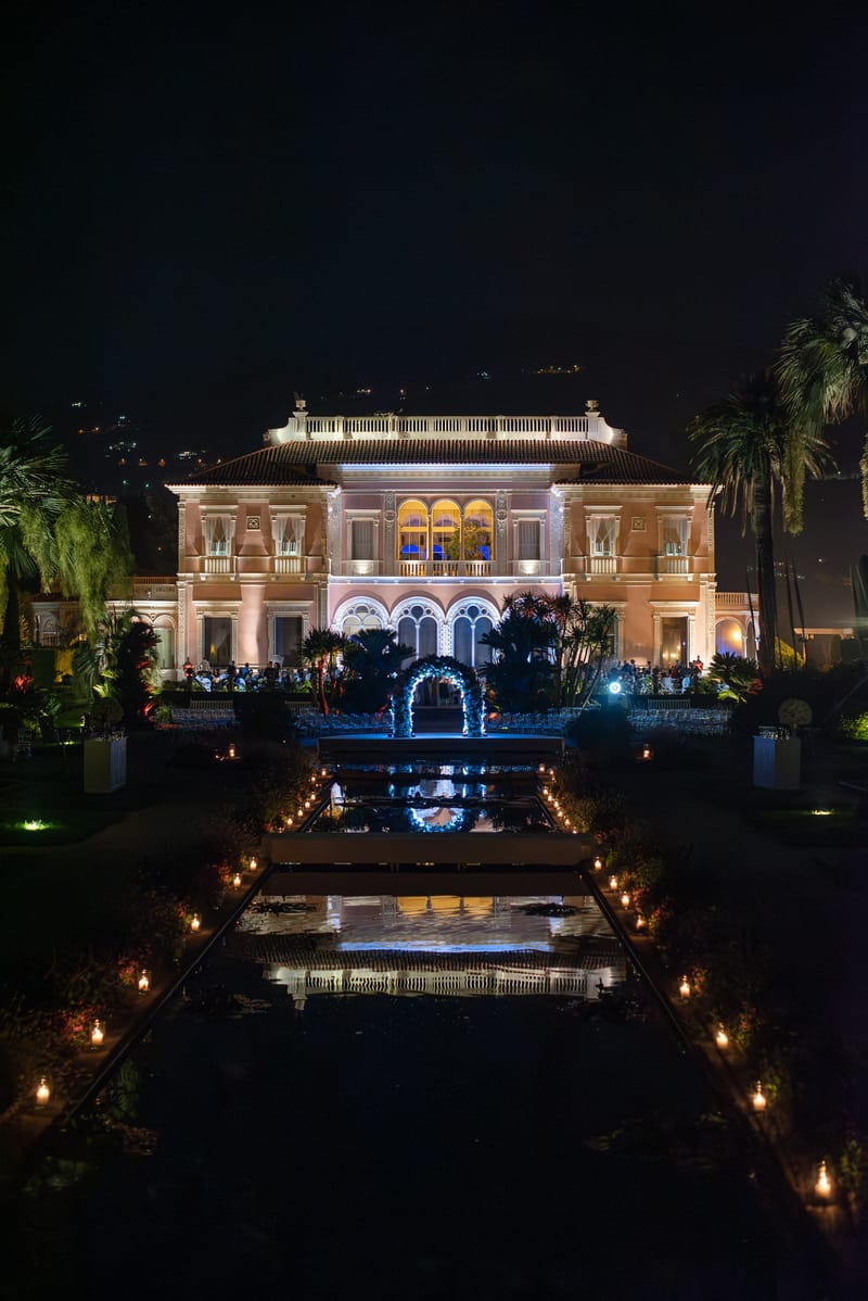 Nighttime wedding ceremony at Belle Epoque villa with floral arch, reflecting pool, and candlelit aisle for 100 guests